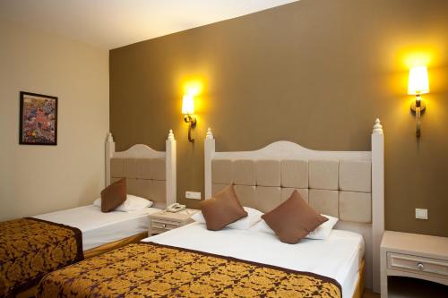シダにあるAdalya Resort & Spa Adults Onlyのベッド2台、壁に照明が備わるホテルルームです。