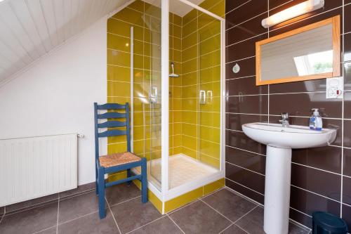 a bathroom with a sink and a shower and a chair at La Maison Bleue 3 étoiles in Plouhinec