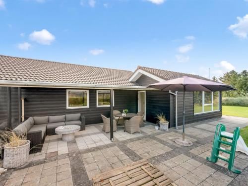 a patio with a couch and an umbrella at Holiday Home Billa - 450m from the sea by Interhome in Blåvand