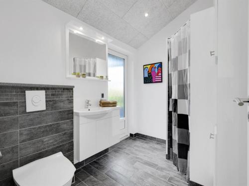 a bathroom with a toilet and a sink and a window at Holiday Home Billa - 450m from the sea by Interhome in Blåvand