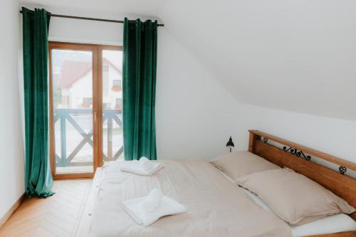a bedroom with a bed with green curtains and a window at Chata Stromček in Zuberec