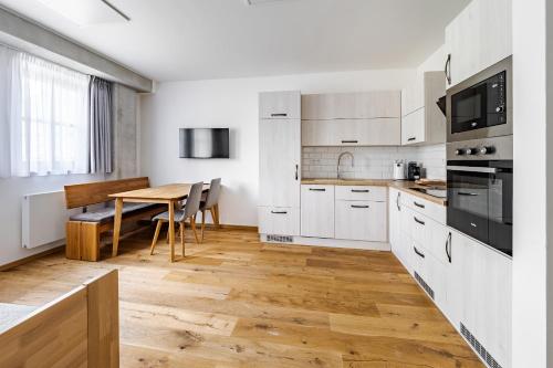 a kitchen with white cabinets and a wooden table at Wellness apartmán Pila Kvilda in Kvilda