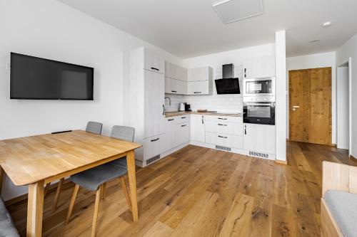 a kitchen with white cabinets and a wooden table at Wellness apartmán Pila Kvilda in Kvilda