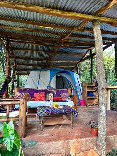 a tent with a bed and a bench in front of it at Jinja Jungle Glamping Tent 2025 in Jinja