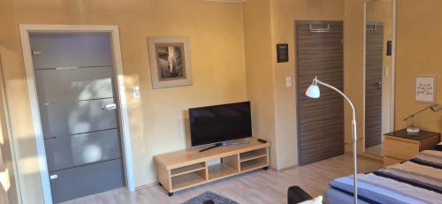 a living room with a television and a bed at FERINO - exklusive Lage , zentral , ruhig in Gütersloh