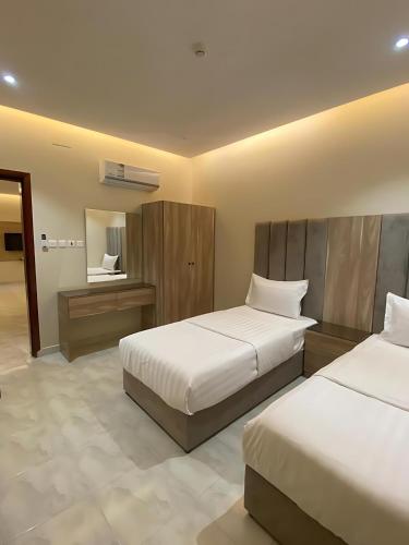 a hotel room with two beds and a mirror at شقق جوهرة الخميس للشقق المخدومة in Khamis Mushayt