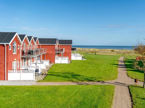 Una casa roja con un patio de césped al lado del océano. en Apartment Vincent - from the sea by Interhome, en Hadsund