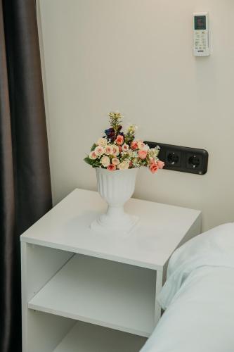 a white table with a vase with flowers on it at Batumi River Source in Batumi
