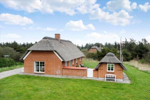 a small house with a thatched roof on a field at 20723-Ulfborg-Sortebaervej-1 in Vedersø Klit
