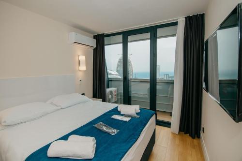 a bedroom with a bed and a large window at Batumi River Source in Batumi