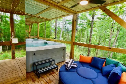 a screened in porch with a blue couch and a tub at 1 of a kind! Largest Transparent Luxe Dome in USA! in Forks of Ivy
