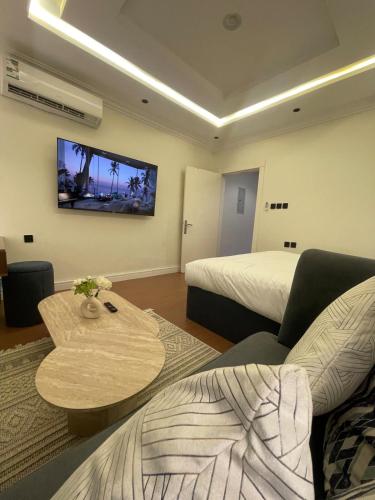a room with two beds and a table and a tv at Modern Studio in Al Malqa Riyadh Near to KAFD-Blvd in Riyadh