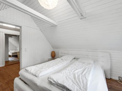 a white bedroom with a bed with white sheets at Holiday Home Matilda - 1-6km from the sea by Interhome in Ulfborg