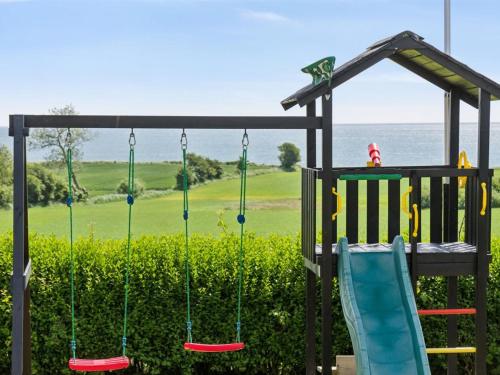 a playground with three swings and a slide at Holiday Home Imilie - 450m from the sea by Interhome in Tranekær