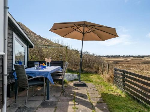 a table with an umbrella on a patio at Holiday Home Sella - 600m from the sea by Interhome in Blokhus