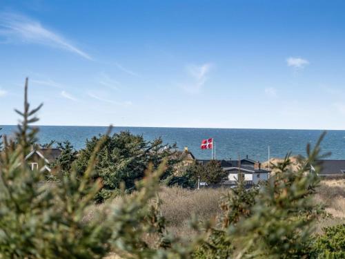 a view of the ocean from the beach with a canadian flag at Holiday Home Sella - 600m from the sea by Interhome in Blokhus
