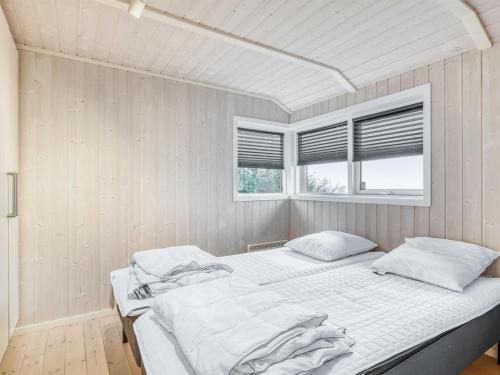 a white bedroom with two beds and a window at Holiday Home Næwe - 10m to the inlet by Interhome in Roslev