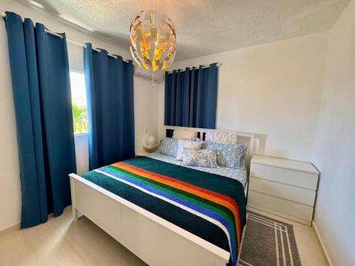 a bedroom with a bed with blue curtains and a chandelier at Bayahibe Apartment by the Beach in Bayahibe