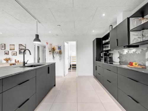 a kitchen with black cabinets and a white floor at Holiday Home Elisaveta - 400m to the fjord by Interhome in Vemb