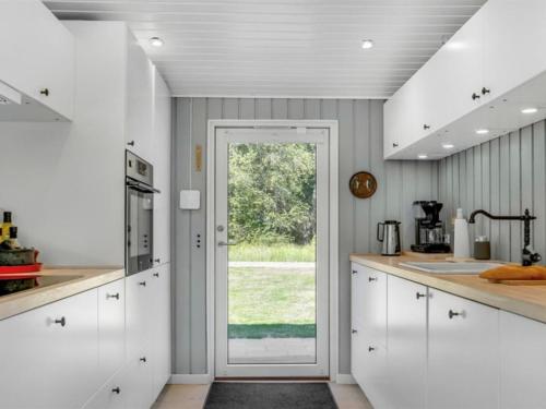 una cocina con armarios blancos y una puerta corredera de cristal en Holiday Home Quiana - 2km from the sea by Interhome, en Pandrup
