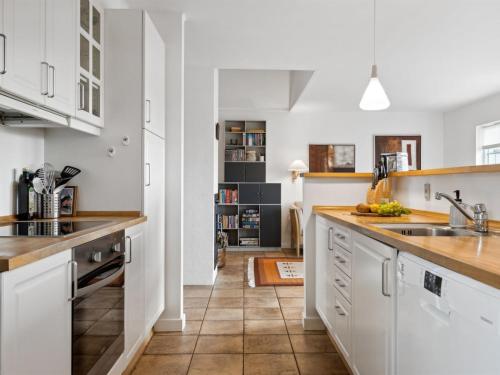 a kitchen with white cabinets and a tile floor at Holiday Home Sakari - 375m from the sea by Interhome in Bro