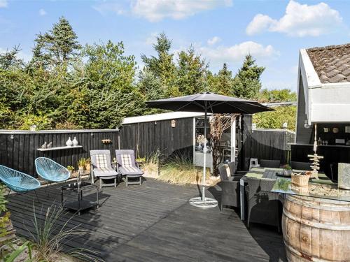 a patio with an umbrella and chairs and a table at Holiday Home Gonda - 2km from the sea by Interhome in Saltum