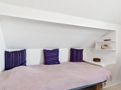 a bed with purple pillows in a room at Apartment Annvy - 1km from the sea by Interhome in Neksø