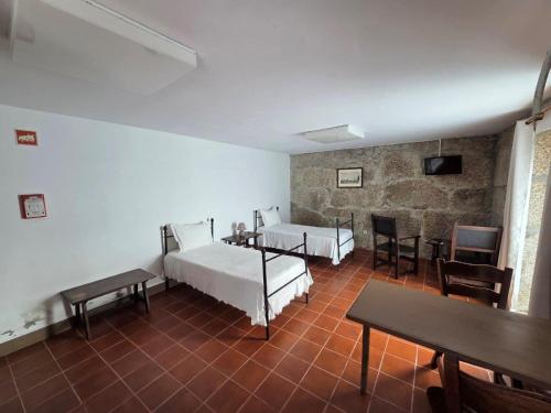 a room with two beds and a table and chairs at Casa dos Bernardos in Terras de Bouro