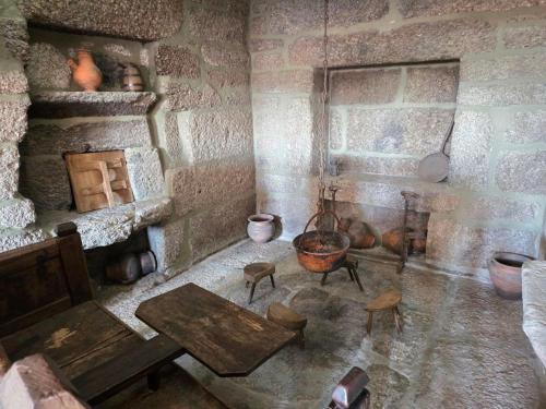 a room with a stone wall with a table and a fireplace at Casa dos Bernardos in Terras de Bouro