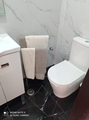 a bathroom with a white toilet and towels at A Casinha in Nazaré