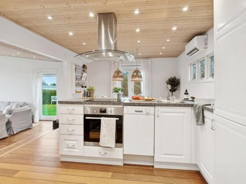 a kitchen with white cabinets and a wooden ceiling at Holiday Home Eero - 175m to the inlet by Interhome in Grevinge