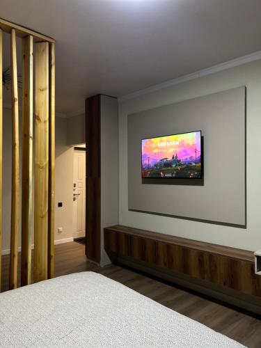 Un dormitorio con un televisor de pantalla plana en la pared. en Little Comfort Home, en Karakol