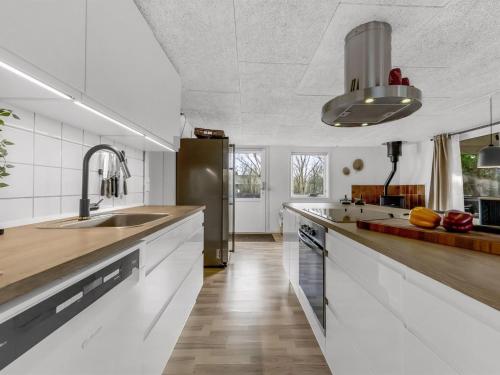 a kitchen with white cabinets and a stainless steel refrigerator at Holiday Home Tiina - 500m to the fjord by Interhome in Tarm