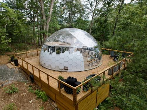 a domed building on a wooden deck with a house at 1 of a kind! Largest Transparent Luxe Dome in USA! in Forks of Ivy