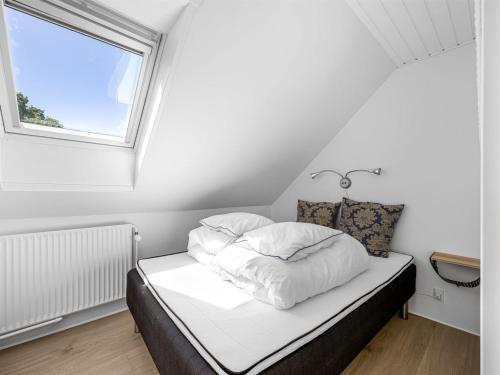a bedroom with a bed with white sheets and a window at Holiday Home Solvey - 400m from the sea by Interhome in Sæby