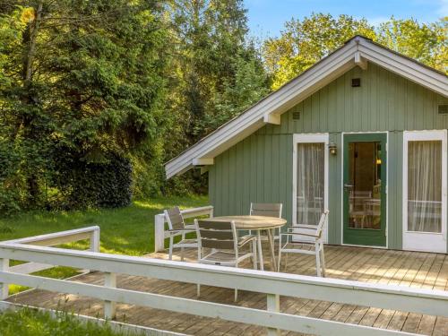 a green cottage with a table and chairs on a deck at Holiday Home Ung - 30km from the sea by Interhome in Toftlund