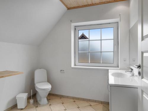 a white bathroom with a toilet and a window at Holiday Home Romy - 450m from the sea by Interhome in Bagenkop