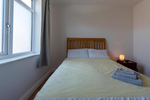 a bed sitting in a bedroom with a window at Luxury 1st floor modern flat, close to city with free parking in Leeds