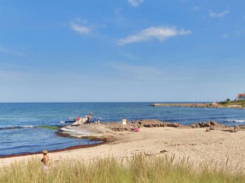 a person walking on a beach near the ocean at Apartment Kate - 300m from the sea by Interhome in Allinge