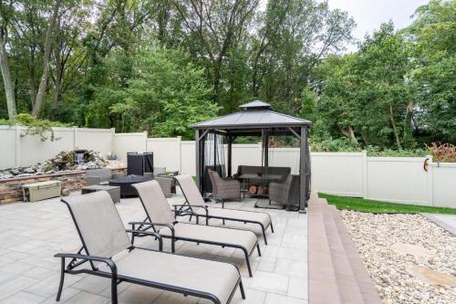 a patio with chairs and a gazebo at Luxury 6BR House with Pool & Outdoor BBQ in Plainview