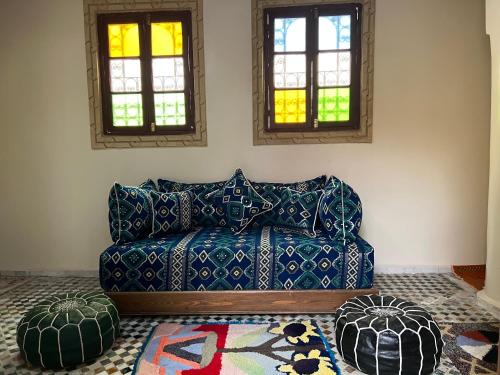 a living room with a blue couch and two windows at Riad Serendipity in Fès