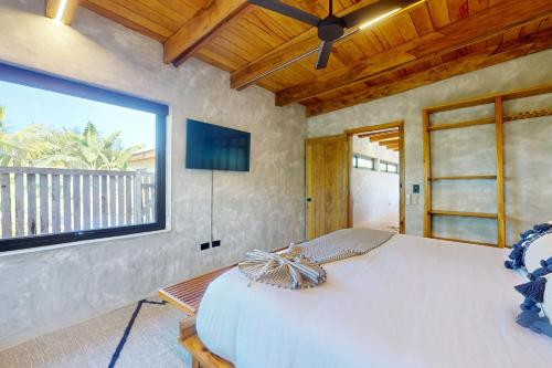 a bedroom with a large bed and a large window at Seabird - Villa 13 in Placencia Village