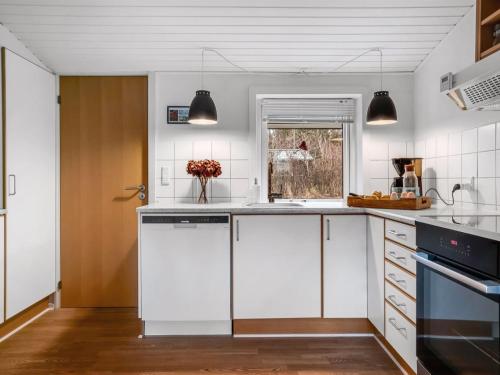 a kitchen with white cabinets and black appliances at Holiday Home Birla - 900m from the sea by Interhome in Hjørring