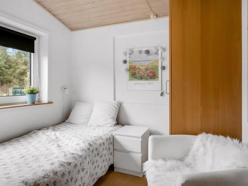 a small bedroom with a bed and a chair at Holiday Home Birla - 900m from the sea by Interhome in Hjørring