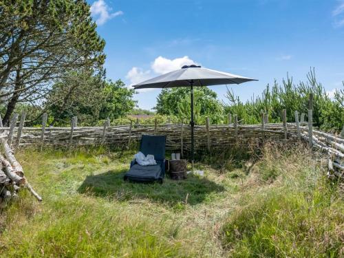 a chair and an umbrella in a field at Holiday Home Fatima - 1km from the sea by Interhome in Fanø