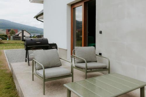 a patio with two chairs and a table and a grill at Chata Stromček in Zuberec
