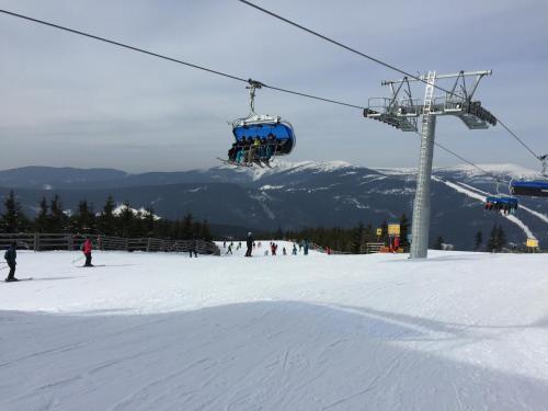 um grupo de pessoas a andar de teleférico na neve em Luční dům em Špindlerŭv Mlýn