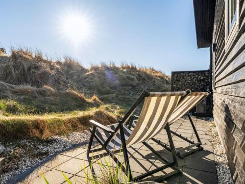 a rocking chair sitting on a sidewalk next to a building at Holiday Home Alrike - 200m from the sea by Interhome in Brovst