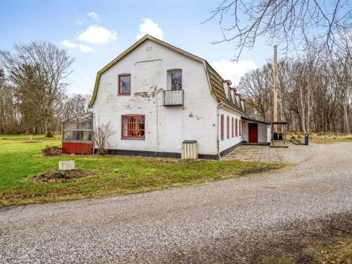 an old white house with red windows on a road at Holiday Home Eva - 9km to the fjord by Interhome in Brovst