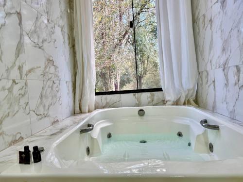 a white bath tub in a bathroom with a window at Hotel Fazenda Vale Alvorada in Cascavel